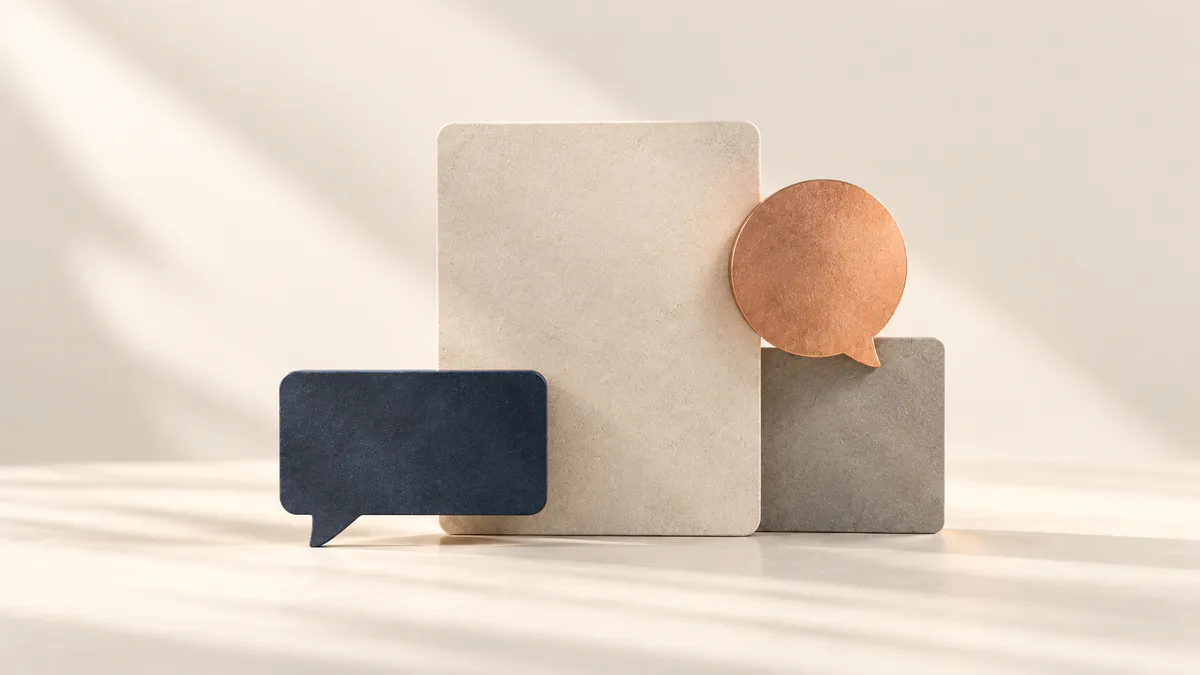 Cream stone panel with a navy speech bubble at lower left and a copper speech bubble resting on a grey block at right