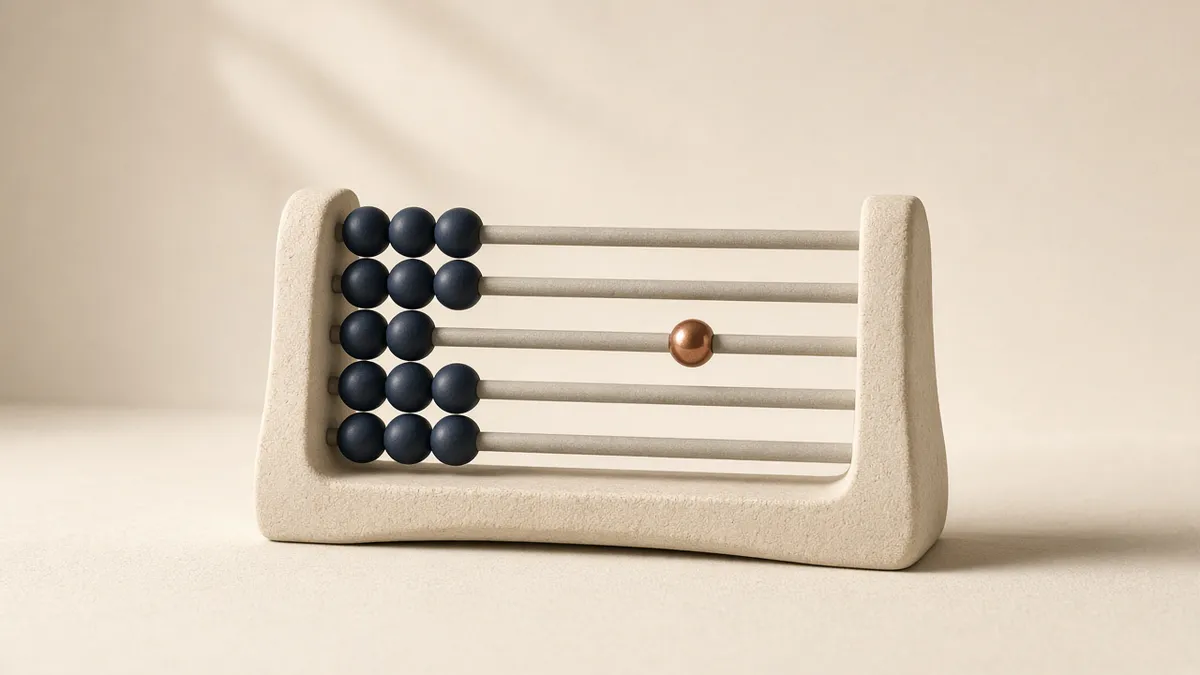 A cream stone abacus with rows of navy beads pushed to one side and a single copper bead sitting alone on the middle rod, against a warm cream wall.